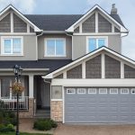 New two-storied gray brick cottage with garage on first floor.